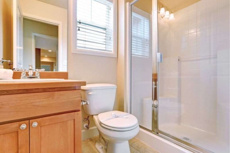 Bathroom with a timber vanity, toilet and framed glass shower with wall lighting