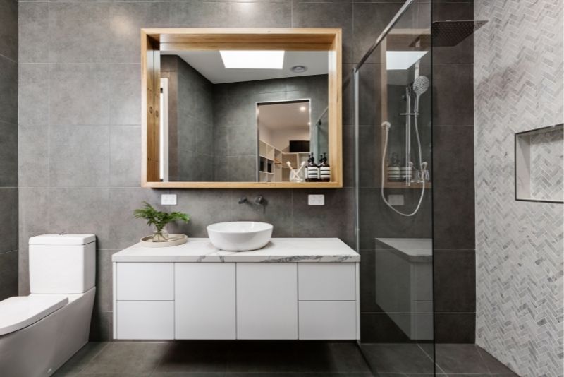 Renovated bathroom with a floating white vanity, timber-framed mirror and frameless glass shower